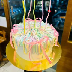 A close-up of a pastel ribbon cake, highlighting the delicate piping work and the soft, appealing color palette.