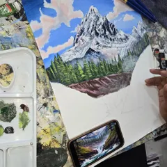 See the process come to life. Here, a student works on a detailed acrylic landscape, learning to layer colors and build depth by referencing a photograph, with all the necessary materials at their fingertips.