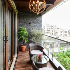 A perfect example of a modern and functional balcony. This space features durable wooden deck flooring, a stylish slate wall cladding, and comfortable wicker seating, all framed by a sleek glass railing to maximize the city view.