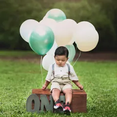 A dreamy outdoor first birthday shoot. This little boy looks so peaceful with his balloons, celebrating his big day in nature.