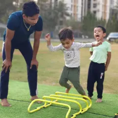 A coach guides our youngest members through agility drills. These fun exercises with hurdles improve coordination, speed, and motor skills.