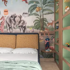 A close-up of the jungle mural and custom shelving unit. Every detail, from the colorful animals to the built-in nightstand, was designed to spark imagination and create a cozy, personalized space.