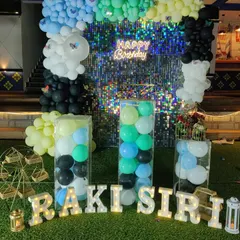 A colorful shimmer wall decoration with a multi-colored balloon arch and transparent plinths filled with balloons.