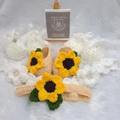 A beautiful display of some of my favorite baby shoe designs. This photo shows a cheerful sunflower-themed booties and headband set alongside a classic white pair decorated with delicate pearls.