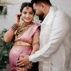 A tender moment between a couple during their traditional baby shower photoshoot. The husband gently holds his wife's baby bump, a simple gesture full of love and anticipation.