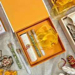 This wedding invitation box for Shambhavi and Joshua features a vibrant, hand-illustrated floral design. Inside, a custom scroll is nestled alongside glass tubes containing traditional spices, offering a multi-sensory experience for guests.
