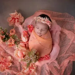 A cocoon of peach-colored lace and flowers. The monochromatic color scheme is soft, elegant, and timeless, creating a truly artistic portrait.
