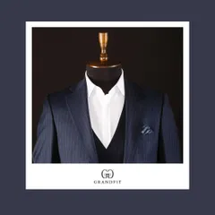 A detailed shot of the navy pinstripe suit, showing the crisp white shirt and the deep V of the waistcoat, creating a clean and structured look.