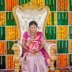 A quiet moment of reflection for the mother-to-be, seated elegantly on the ceremonial chair, surrounded by traditional decorations.