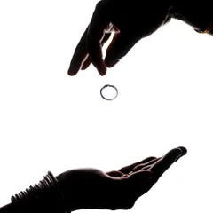An artistic silhouette capturing the moment a ring is dropped from one hand to another, symbolizing the exchange.