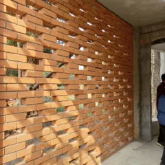 The texture of a perforated brick wall at the Kolgaon site. We use local brick not just for structure, but as a tool to control light, provide natural ventilation, and give a unique identity to each home.