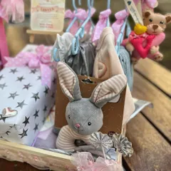 A close-up of the mini clothing rack, showing tiny outfits hung on individual hangers, each adorned with a delicate bow.
