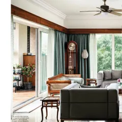 The living room connects seamlessly to a double-height deck, blurring the lines between indoors and outdoors. The design balances modern grey sofas with antique wooden furniture, like the stately grandfather clock.