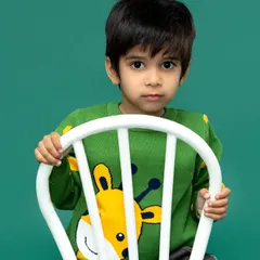 A striking and simple portrait against a solid green backdrop. Sometimes, a direct gaze and a simple setting are all that's needed to capture a child's powerful presence.