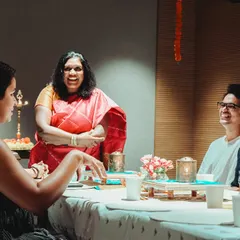A candid moment of laughter and conversation around a table during a community gathering.