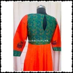 The back of the orange and green Anarkali gown. It features a simple keyhole cutout, allowing the rich green brocade fabric to be the main focus.