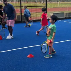 Our coaches are hands on, ensuring every child gets the attention they need. This young player is learning ball control and coordination, key skills that we build upon in our kids' tennis training sessions.