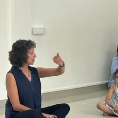 In a quiet moment, Naheed uses hand gestures to communicate a musical concept. This highlights the importance of non-verbal cues and expressive instruction in teaching young, pre-literate children.