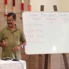An instructor explains the conceptual framework of Pranayama during a workshop, using a whiteboard to detail patterns of Puraka (inhalation), Kumbhaka (retention), and Rechaka (exhalation). Our workshops combine deep theory with practical application.