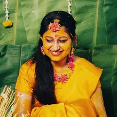A beautiful portrait of the bride covered in turmeric paste, smiling radiantly. The vibrant yellow and her genuine happiness define the spirit of the Haldi.