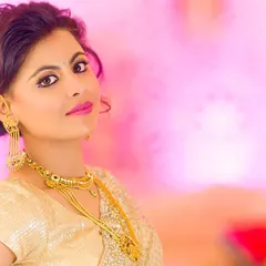 A vibrant bridal portrait using a soft, diffused light to create a flawless look. The pink background complements the bride's golden saree, and the use of a Zeiss lens ensures every detail is captured with sharpness and clarity.