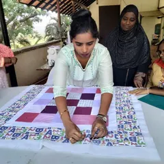 A student in our NGO workshop carefully pinning the layers of her quilt together, a crucial step before the final quilting.