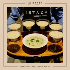 A member of my team holds a beautifully arranged tray of Green Thai Curry and Jasmine Rice, ready to serve guests.