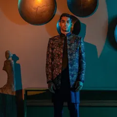 A model stands poised in a dark, intricately embroidered jacket, a key piece from our Raaya collection. This Indo-Western ensemble is designed for the man who appreciates a blend of traditional craft and modern form.