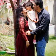A sweet and loving family photograph where both parents kiss their daughter. This image beautifully captures the bond of the existing family unit as they await their new arrival.