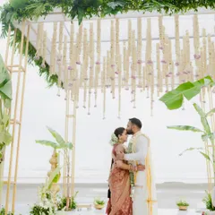 A tender kiss on the forehead at their beachside South Indian wedding. The mandap, adorned with jasmine and banana leaves, beautifully frames this moment of blessing and love.