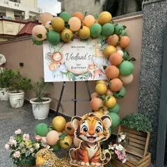 A charming welcome easel for a jungle-themed first birthday party held at home. The setup includes a balloon garland in safari colors and cute animal cutouts.