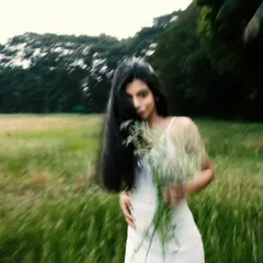 A playful, partially obscured portrait, using a bouquet of wildflowers to add a touch of whimsy and a soft, blurry foreground.
