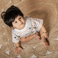 An overhead shot capturing a sweet, curious look. The textures of the jute rug add visual interest to the portrait.