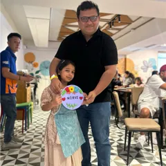 A proud dad with his daughter and the colorful nameplate she painted. Our family workshops are all about creating joy and tangible memories.