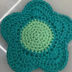 A close-up of one of the flower coasters, showing the two-tone color design and neat spiral stitching in the center.