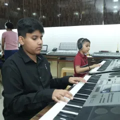 Two young students deeply focused during their keyboard class. We foster an environment where students can learn together, inspiring each other while mastering instruments like the piano and keyboard with modern training techniques.