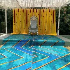 This wide shot shows the complete outdoor stage with its unique blue and gold patterned carpet leading up to the throne. This kind of setup is great for making a bold statement at a sangeet or reception.