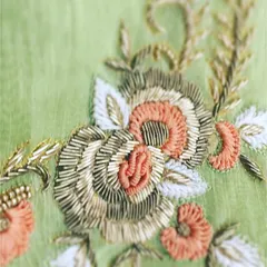 This close-up shows the texture and detail of dabka and zari work. The combination of metallic threads and fine beads creates a three-dimensional floral design that is rich and luxurious.
