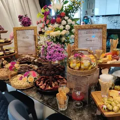 The full view of a decadent grazing table at a private evening celebration. Adorned with fresh flowers, the table features a curated selection of cheeses, desserts, and savoury bites to delight every guest.