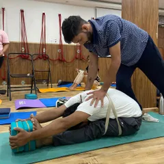 This student is using a strap to help him fold forward from the hips, not the waist. This technique protects the lower back and allows for a much deeper release in the hamstrings and spine.