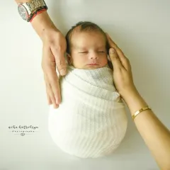 A close-up of parents' hands gently holding their sleeping baby. This pose emphasizes how small and precious your newborn is, creating a memory of those first few days that you'll never want to forget.