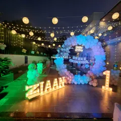 The "ZIAAN" first birthday poolside setup viewed from a different angle, highlighting the glowing marquee letters and the reflection of the lights on the patio.