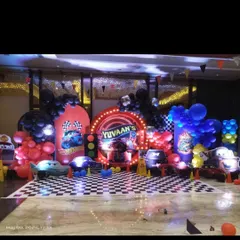 A high-speed Hot Wheels and Cars themed birthday party. The setup includes a checkered flag floor, a custom backdrop with the birthday boy's name, and character cutouts of Lightning McQueen.