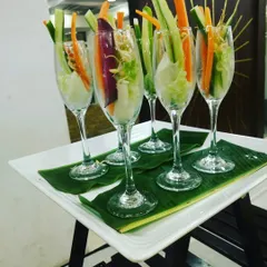 Fresh vegetable sticks and sprouts elegantly arranged in champagne flutes, a healthy and stylish appetizer for any modern event.