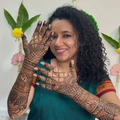 A happy bride showing off her beautiful, full-coverage mehendi. The design is packed with traditional motifs, creating a timeless bridal look.