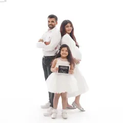 A beautiful family maternity portrait where the big sister-to-be proudly holds up the ultrasound photo, announcing the new arrival.