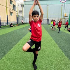 A young player holds a yoga pose with focus and determination, showcasing discipline beyond the football field.