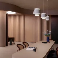 A long, minimalist table is set against a backdrop of undulating walls, showcasing how the space can transform to host meetings or events.