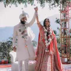 The couple raises their hands in celebration after the jaimala ceremony at their beautiful mountain destination wedding.
