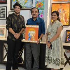 Artist Anjana from Kalagram holds her sold Ganesha painting with its new owner, a happy moment from the "Vernissage" exhibition.